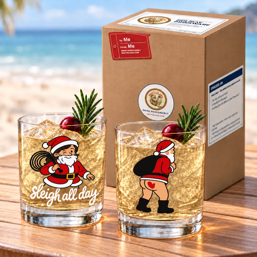 Not So Silent Night gift set: Holi-Flogger and Spanked Nauti Claus rocks glasses beside a kraft gift box on a beach
